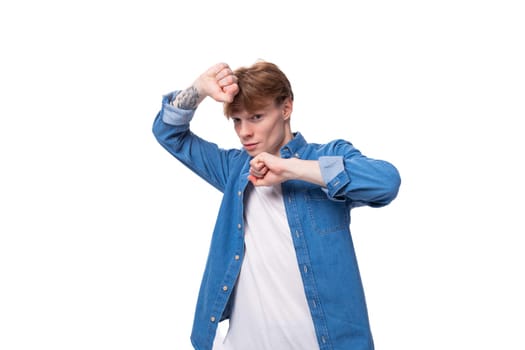 young man with red hair wearing a blue shirt over a white t-shirt.