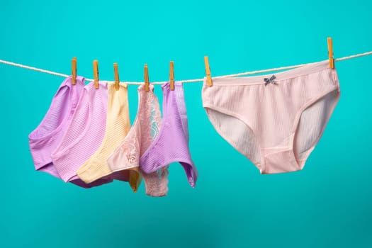 Female panties hanging on rope against blue studio background copy space