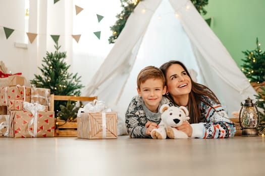 Happy mom and son enjoying Christmas together in cozy decorated home