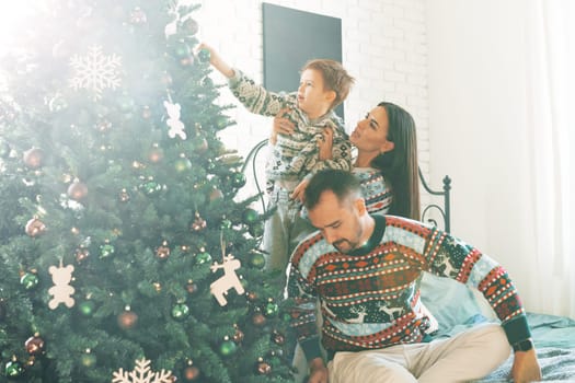 Happy family near fir-tree in bedroom, Christmas celebration at home close up