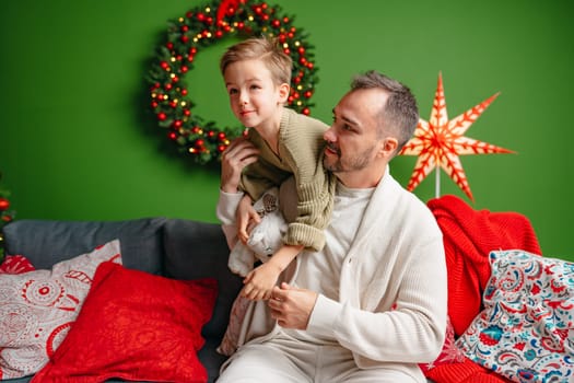 Young dad and his son celebrate Christmas together at home close up