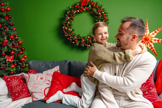 Young dad and his son celebrate Christmas together at home close up