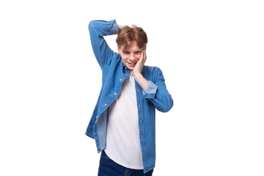 young pretty slender caucasian red-haired man in a denim shirt on a white background with copy space.