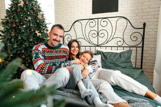 Happy family near fir-tree in bedroom, Christmas celebration at home close up