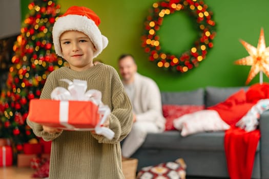 Cute little boy holding a gift box for Christmas at home