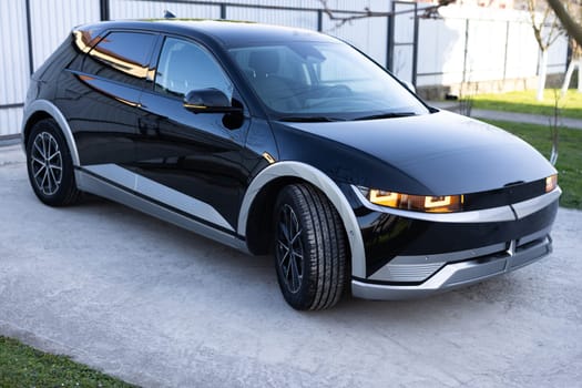 Black color electric car stand by a road . Sport SUV electric vehicle. Concept of presenting new car. Black premium city SUV. Luxury car of business class is parked on city.