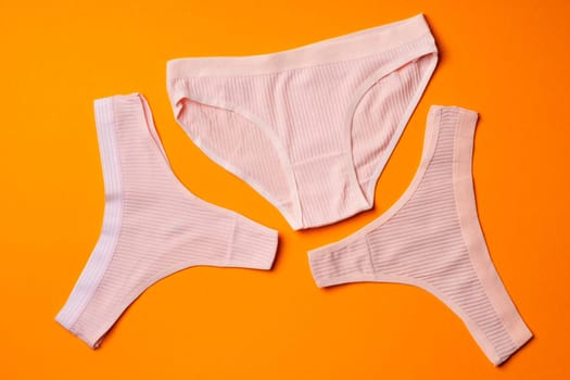 Women's panties on an orange background flat lay top view