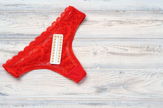 Woman panties with birth control pills top view flat lay