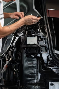 Close up photo of car wrapping specialist putting protective film on a car in detailing service