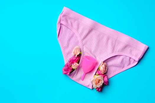 Menstrual cup and panties on paper background, top view