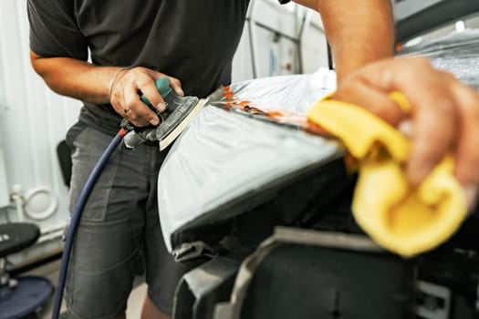 Close up photo of car cleaner polishing headlight with polish machine