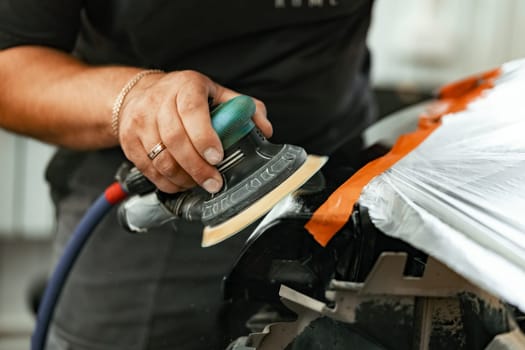 Close up photo of car cleaner polishing headlight with polish machine