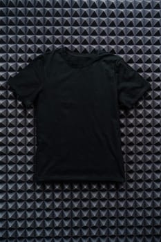 Black color plain t-shirt on textured background top view