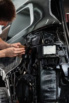 Close up photo of car wrapping specialist putting protective film on a car in detailing service