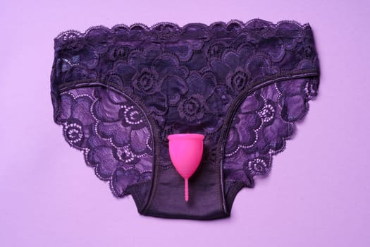 Menstrual cup and panties on paper background, top view