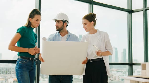 Professional architect engineer team talking, sharing, brainstorming about design while manager hold at project plan. Young architect holding plan while manager listen and point at plan. Tracery