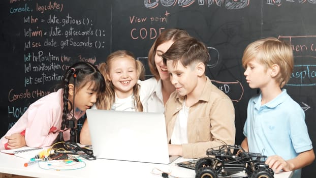 Diverse student writing engineering code while boy fixing mother board. Teacher giving advice and teaching about robotic system while learner studying and learning about coding prompt. Erudition.