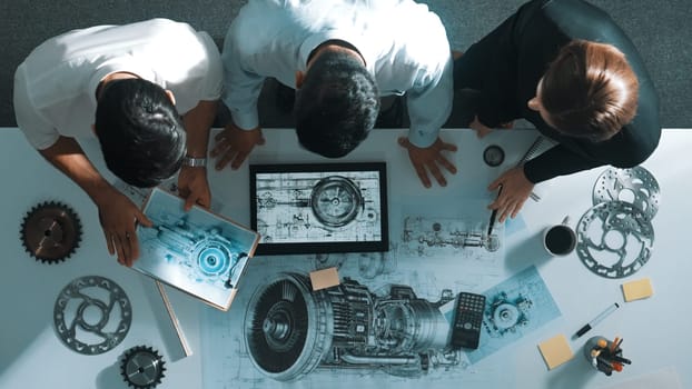 Top down view of skilled engineer working together while looking at jet engine. Aerial view of smart designer or diverse technicians brainstorming while looking at electronic generator. Alimentation.