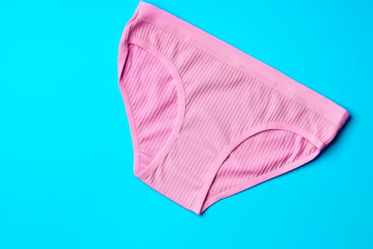 Women's panties on a blue background in studio top view