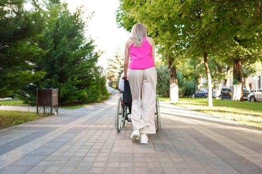 Young female caregiver pushing wheelchair with mature female person with disability across city street