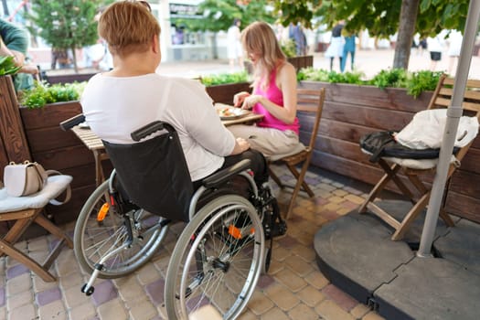 Woman wheelchair user dining at a restaurant with her young daughter, close up