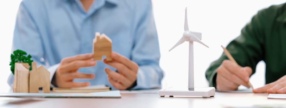 Business people invest in green business plan at meeting room on table with house model and wind mill placed represented eco house and renewable energy. Closeup. Delineation.
