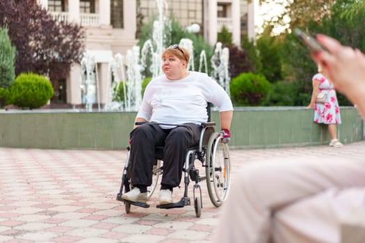 Mature woman with disability sitting in wheelchair outdoors in city