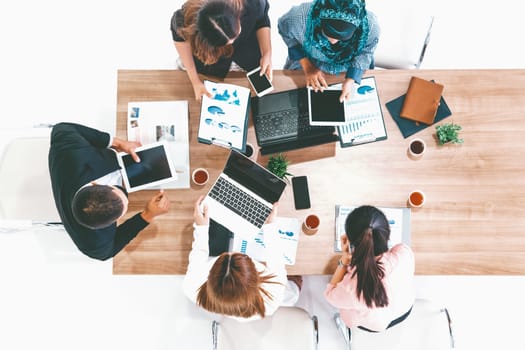 Top view of businessman executive in group meeting with other businessmen and businesswomen in modern office with laptop computer, coffee and document on table. People corporate business team uds