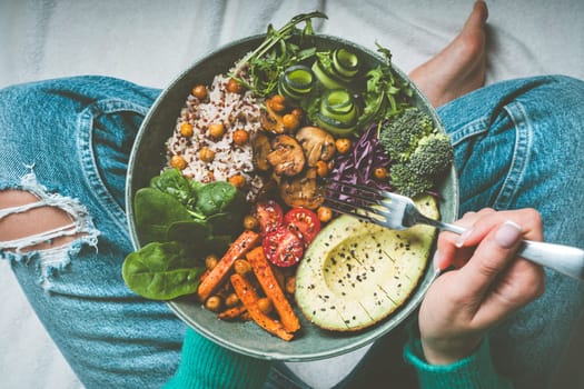 Woman eating healthy meal. Bowl with rice, quinoa, avocado, cucumber, broccoli and cucumber. Healthy diet, lunch or dinner. Healthy food plate. High quality photo