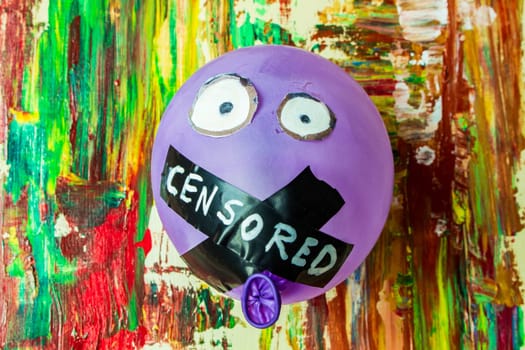 In a vivid juxtaposition of color and constraint, behold this symbolic image featuring a balloon with its mouth taped shut, suspended against a backdrop of vibrant, colorful painting