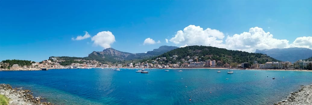 A sweeping view captures the essence of a bustling coastal town, nestled between azure waters and lush mountain scenery.