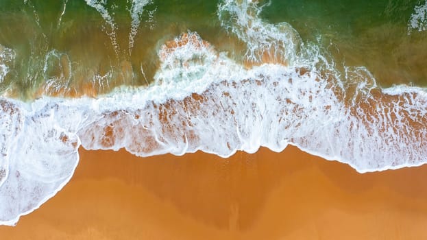 Drone view of beautiful seamless footage while turquiose sea waves breaking on sandy coastline. Aerial shot of golden beach meeting deep blue ocean water and foamy waves