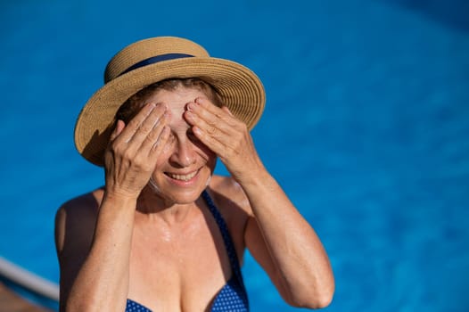 Portrait of an older woman applying sunscreen to her face while on vacation