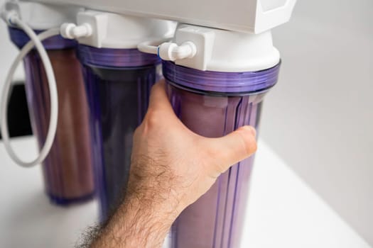 Man hand opens the reverse osmosis system for water purification at home.