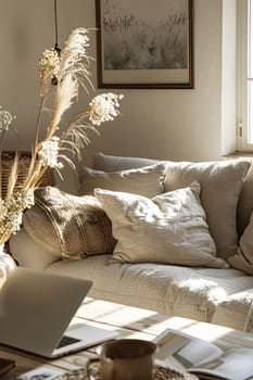 A cozy living room with a comfortable couch and a laptop on a wooden table. The interior design includes hardwood flooring, a picture frame, and a window for natural light