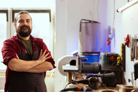 Portrait of upbeat woodworking professional preparing to start production in messy furniture assembly shop. Cheerful craftsperson in studio at workbench ready to cut wood pieces