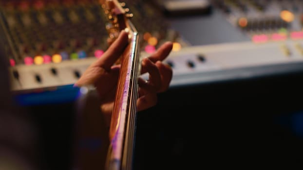 Musician singer recording a new song on his electro acoustic guitar, creating new music in professional studio control room. Artist doing live performance with instrument. Close up. Camera A.