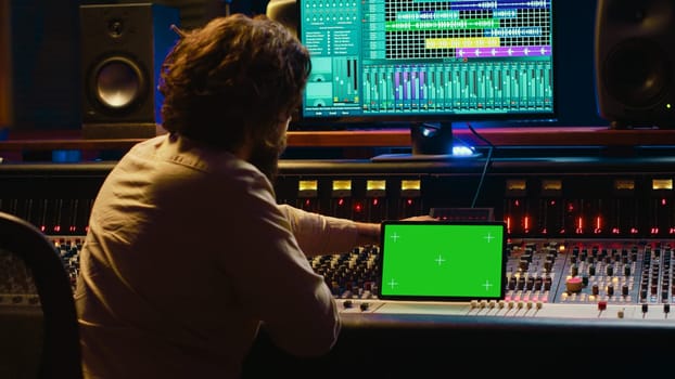 Audio technician working with music recording software and editing tunes, mixing console and control panel board in post production studio. Producer operating technical equipment. Camera A.