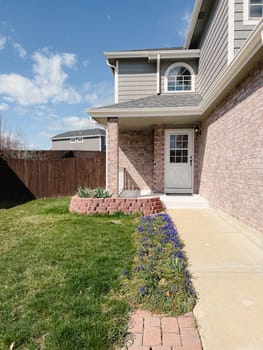 charming front yard of a suburban house, basking in the warm glow of sunlight, with well-manicured lawns and colorful flowers adding to its appeal.