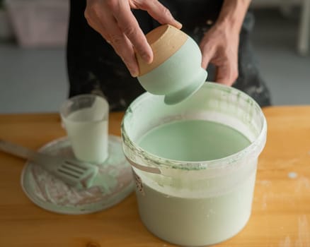 Close-up of a potter's hands glazing a pottery piece