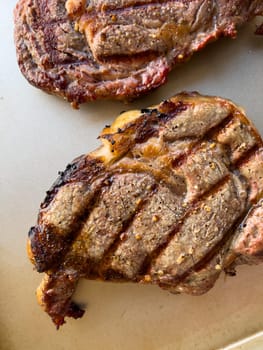 succulent texture of three ribeye steaks grilled to perfection, featuring charred edges and distinct grill marks, showcased on a neutral background.