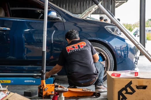 Bangkok, Thailand - February 4, 2023 : Unidentified car mechanic or serviceman disassembly and checking a disc brake and asbestos brake pads for fix and repair problem at car garage or repair shop