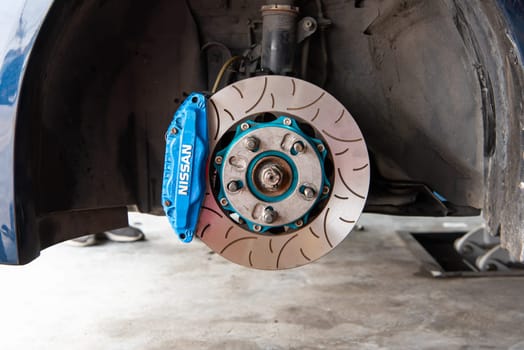 Bangkok, Thailand - February 4, 2023 : Unidentified car mechanic or serviceman disassembly and checking a disc brake and asbestos brake pads for fix and repair problem at car garage or repair shop