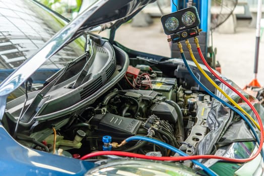 Bangkok, Thailand - May 4, 2023 : Unidentified car mechanic or serviceman refilling air condition and checking a air compressor for fix and repair problem at car garage or repair shop