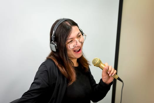 Beautiful asian woman (LGBTQ) is a singer. She enjoying sing a song or karaoke in music studio with microphone condenser and headphones for fun or voice creative