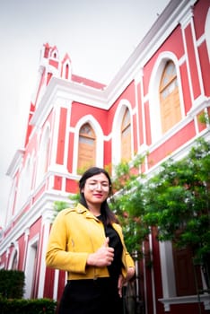 Beautiful asian woman (LGBTQ) natural makeup wear fashion yellow leather clothes with glasses posing at old town and vintage building outdoor fashion style