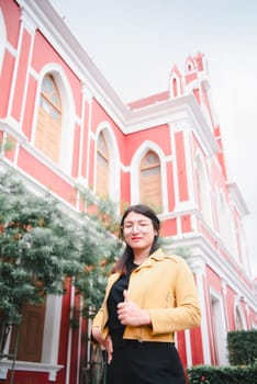 Beautiful asian woman (LGBTQ) natural makeup wear fashion yellow leather clothes with glasses posing at old town and vintage building outdoor fashion style