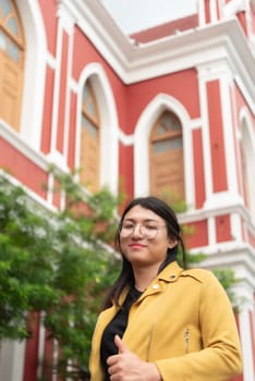 Beautiful asian woman (LGBTQ) natural makeup wear fashion yellow leather clothes with glasses posing at old town and vintage building outdoor fashion style