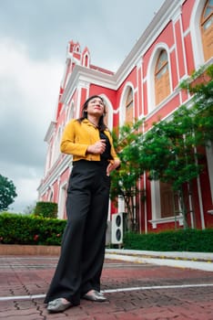 Beautiful asian woman (LGBTQ) natural makeup wear fashion yellow leather clothes with glasses posing at old town and vintage building outdoor fashion style