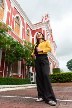 Beautiful asian woman (LGBTQ) natural makeup wear fashion yellow leather clothes with glasses posing at old town and vintage building outdoor fashion style